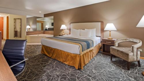 um quarto de hotel com uma cama e uma cadeira em Best Western West Towne Suites em Madison