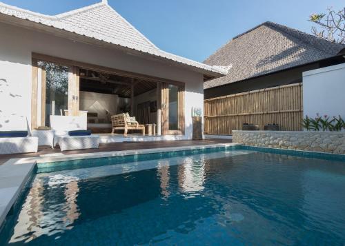 
a swimming pool with a couch and a chair in it at Aloha Beach House Bingin in Uluwatu
