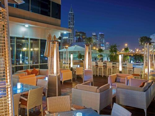 a restaurant with chairs and tables and a city skyline at Pullman Dubai Jumeirah Lakes Towers in Dubai