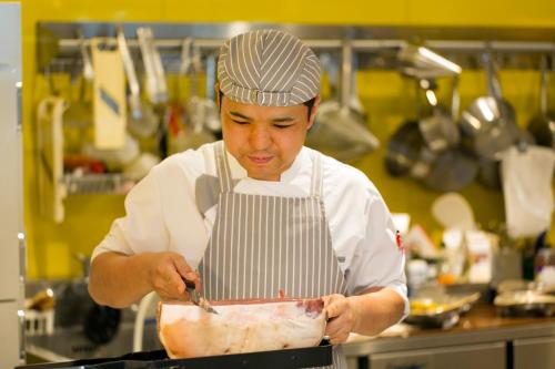 a man in a kitchen preparing food in a pan at Hotel Monterey Le Frere Osaka in Osaka