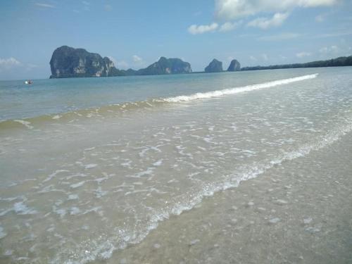 a sandy beach with rocks in the water at Fisherman's Hut , ขนำชาวเลโฮมสเตย์ in Pak Meng