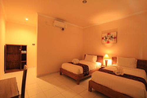 a hotel room with two beds and a window at Ayuna Family Ubud in Ubud