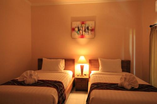 a hotel room with two beds and a lamp at Ayuna Family Ubud in Ubud