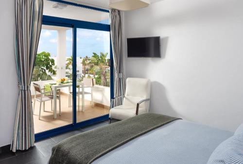 a bedroom with a bed and a balcony with a table at Villas de la Marina in Playa Blanca
