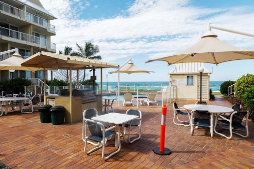 a patio area with chairs, tables and umbrellas at Crystal Beachfront Apartments in Gold Coast