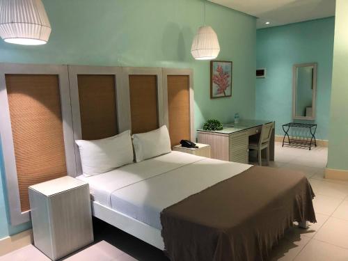 a bedroom with a large bed and a desk at Hotel Lorenza in Tacloban