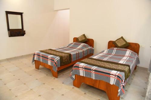 2 Betten in einem Zimmer mit einem Wandspiegel in der Unterkunft Vamoose Hideaway in Chikmagalur