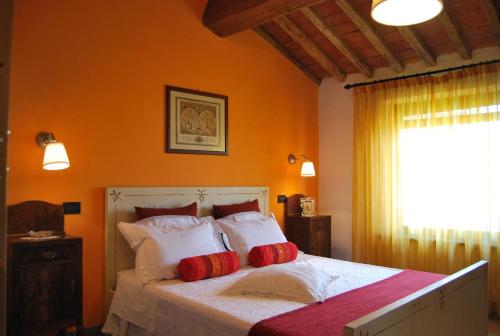 Schlafzimmer mit einem Bett mit roten und weißen Kissen in der Unterkunft Il Cantuccio in Cascina