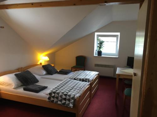 捷克布傑約維采的住宿－米爾托姆旅館，一间卧室设有两张床、一张桌子和一个窗口。