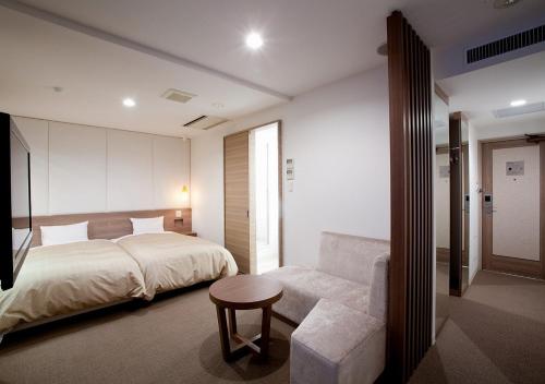 a bedroom with a bed and a chair and a couch at Hotel Sorriso Hamamatsu in Hamamatsu