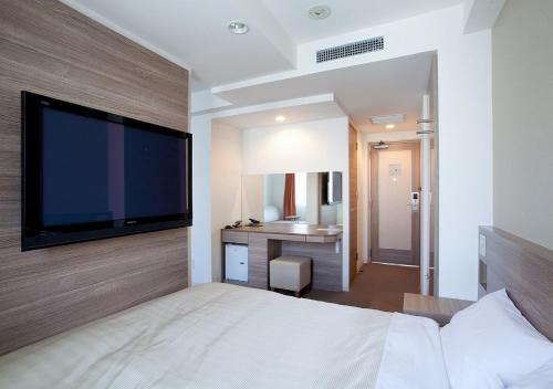 a bedroom with a large flat screen tv on a wall at Hotel Sorriso Hamamatsu in Hamamatsu