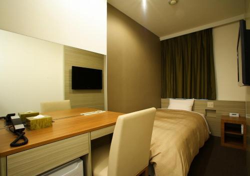 a room with a desk and a bed with a telephone at Hotel Sorriso Hamamatsu in Hamamatsu