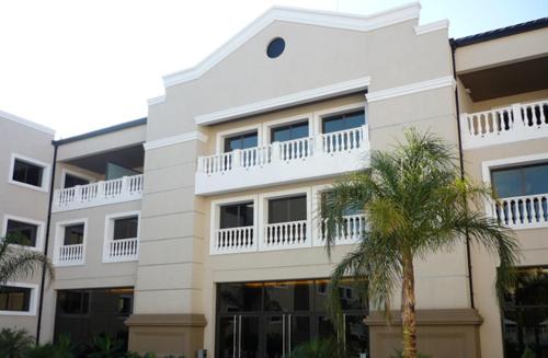 a white building with a balcony and a palm tree at Howard Johnson Hotel & Casino in Formosa