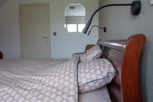 a bed in a room with a lamp on the wall at Vakantiewoning Pelterheggen in Grote Heide