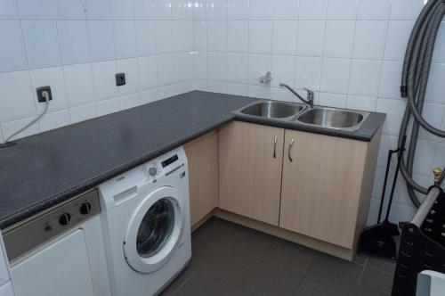 a kitchen with a sink and a washing machine at Vakantiewoning Pelterheggen in Grote Heide