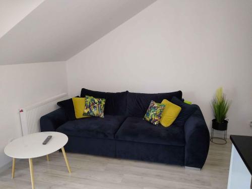 a living room with a blue couch with yellow pillows at Apartament Kruklanki in Kruklanki