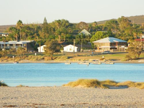 a beach with houses and boats in the water at API Pelican Beach Front Apartments Kalbarri in Kalbarri