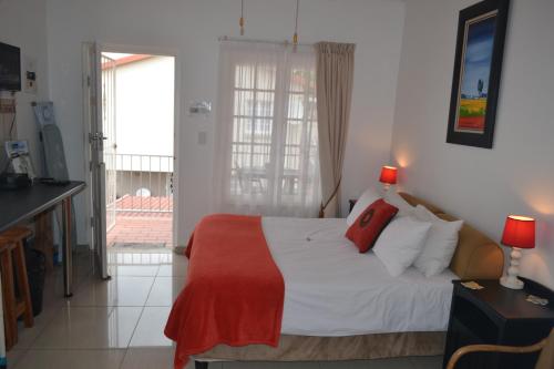 a bedroom with a bed with a red blanket on it at Driftsands Sea View Flats in Uvongo Beach