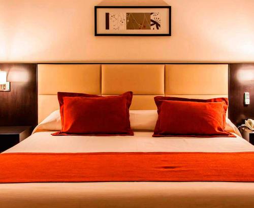 a bedroom with a large bed with red pillows at Howard Johnson Hotel & Casino in Formosa