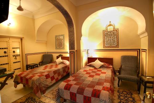 a bedroom with two beds and chairs in a room at Khatu Haveli in Jaipur