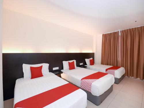 a hotel room with two beds with red pillows at Kenyalang Suite in Miri