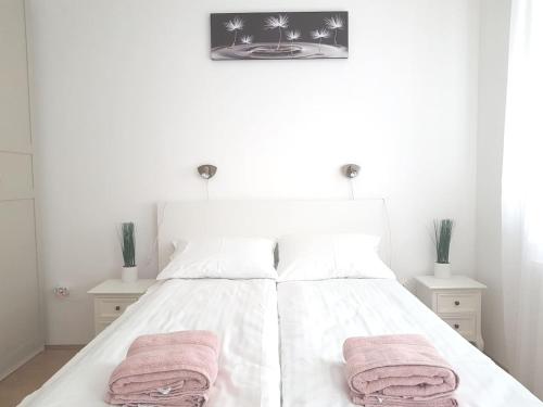 - une chambre avec un lit blanc et 2 serviettes dans l'établissement Központhoz közeli - Cool Tettye Apartman, à Pécs