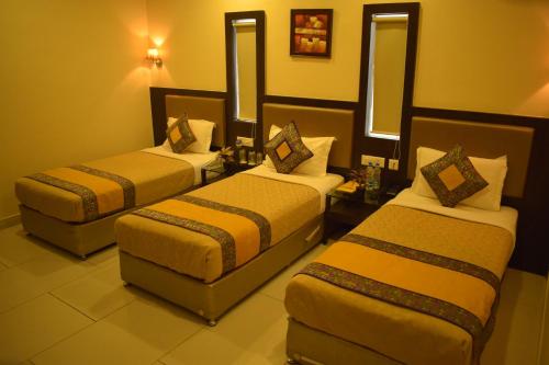 una habitación de hotel con tres camas y un sofá en Hotel Hari Vilaas, en Varanasi
