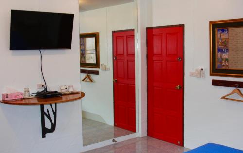 two red doors in a room with a tv at Tea Moon Beach House in Thongsala