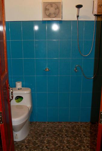 a blue tiled bathroom with a toilet and a shower at Tea Moon Beach House in Thongsala