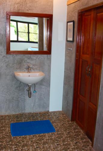 a bathroom with a sink and a mirror and a door at Tea Moon Beach House in Thongsala
