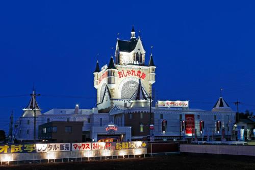 a large building with a clock tower at night at Osyare Kizoku Ichinomiya (Adult Only) in Ichinomiya