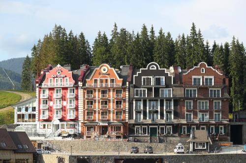 a group of buildings sitting next to a river at Petros Hotel in Bukovel