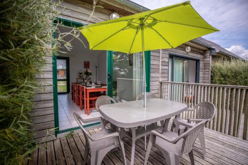 une table et des chaises avec un parasol jaune sur une terrasse dans l'établissement Village Beauséjour - Rêves de mer, au Conquet