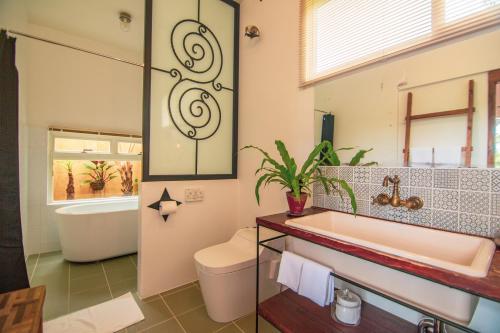 ein Badezimmer mit einer Badewanne, einem WC und einem Waschbecken in der Unterkunft Somos in Nakijin