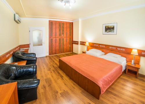 a hotel room with a bed and leather chairs at Hotel Silver in Hajdúszoboszló