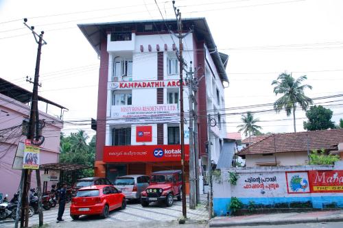 a tall building with cars parked in front of it at Misty Rosa Resorts Pvt Ltd in Kottayam