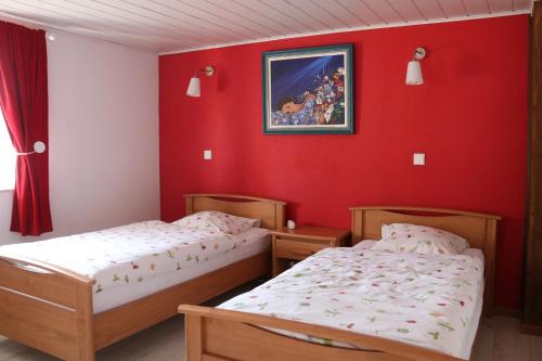 2 Betten in einem Zimmer mit roten Wänden in der Unterkunft Simonshome in Sarre-Union