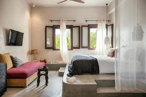 a bedroom with a bed and a couch and windows at Casita Casita Lindos - Adults Only in Líndos