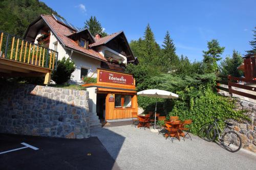 a building with a table and chairs and an umbrella at Vila Edelweiss Rooms&App Kranjska Gora in Kranjska Gora