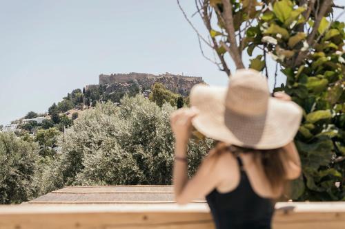 a woman wearing a hat looking at a mountain at Casita Casita Lindos - Adults Only in Líndos