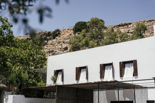 a white building with a mountain in the background at Casita Casita Lindos - Adults Only in Líndos