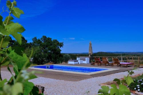 a swimming pool in a yard with chairs and an umbrella at Cal Velho - Holiday Lodge in São Luis