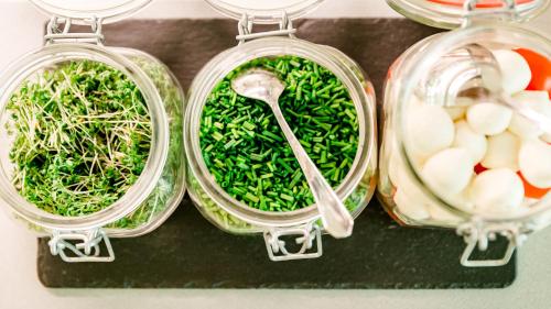 four glass jars filled with vegetables and a spoon at Thermalhotel Gass in Bad Füssing