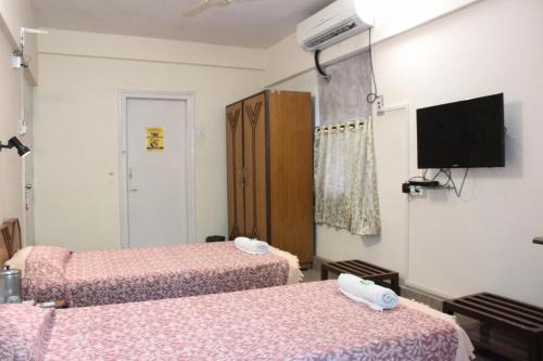 a room with two beds and a flat screen tv at YWCA International Centre in Mumbai