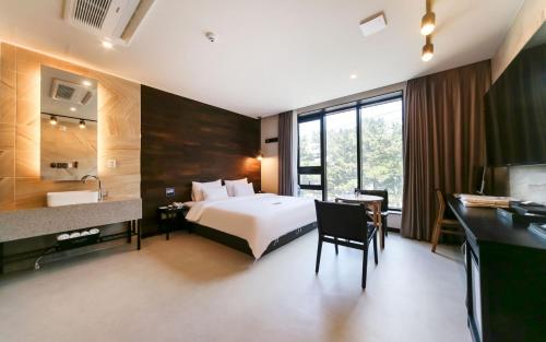 慶州市にあるLe Idea Gyeongjuのベッドと机と洗面台があるホテルの部屋