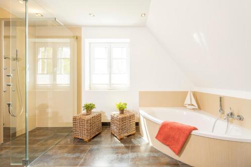 a white bathroom with a tub and two plants at Ferienhaus Dünenwind in Sankt Peter-Ording