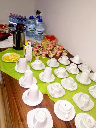 a table with white cups and plates on a table at Zajazd Irys in Sosnowiec