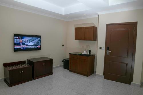 um quarto com uma televisão na parede e uma porta em Monarch Hotel em Accra