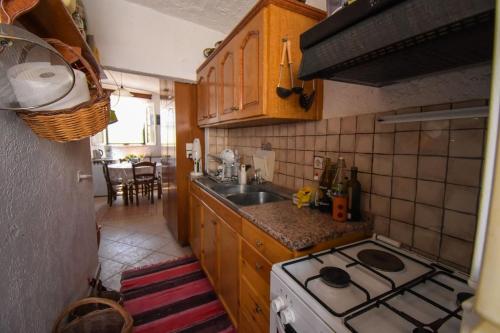 uma pequena cozinha com um fogão e um lavatório em The little house on the hill of Myrties em Myrties