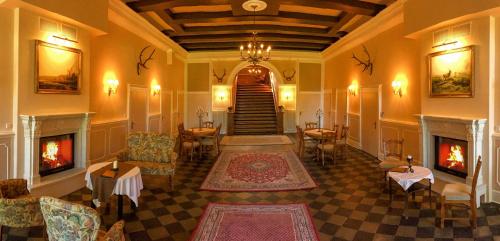a lobby with a fireplace and a staircase with tables and chairs at Jagdschloß Walkenried in Walkenried